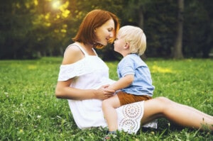 Happy Single Mother With Her Son Playing On Green Grass