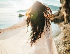 Healthy Woman Running dreamy with wind in hair and sunflare on beach sunset